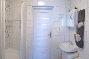 a white bathroom with a shower and a sink at Apartament z garażem w Kołobrzegu in Kołobrzeg