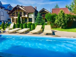 a group of lounge chairs and a swimming pool at Villa Diola in Kosiv