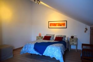 sypialnia z łóżkiem z niebieską kołdrą i czerwonymi poduszkami w obiekcie El Ático de La Casa Viva w mieście Vélez Blanco