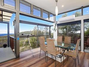 une salle à manger avec une table et des chaises en verre dans l'établissement Beach House 7 26 One Mile Close air conditioned wifi foxtel linen, à Anna Bay