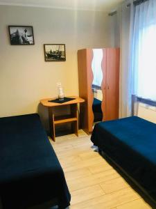 a room with two beds and a table and a desk at Pokoje i Apartamenty 200 m do plaży in Karwia