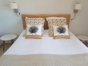 a white bed with two pillows and two tables at Le Mas du Lingousto in Cuers