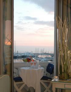 a table with glasses on a balcony with a view of a harbor at Hotel Splendid in Cannes