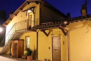 a yellow house with a wooden door and stairs at C&C Il Treggio in Foligno