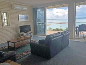 a living room with a couch and a tv and a table at Classic View 1, 1 49 Victoria Parade - panoramic water views, aircon and Wifi in Nelson Bay