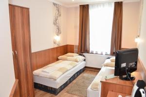 a hotel room with two beds and a television at Média Panzió és Apartmanház in Hajdúszoboszló