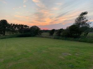 a large green field with a sunset in the background at The Cabin in Millom