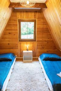 2 łóżka w pokoju z drewnianymi ścianami i oknem w obiekcie DOM LAS - natura, relaks, jacuzzi. w mieście Mianów