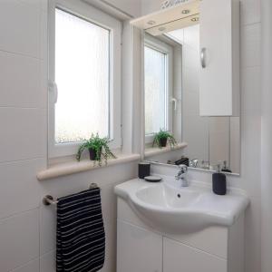 La salle de bains blanche est pourvue d'un lavabo et d'un miroir. dans l'établissement Apartments Valentina, à Bol