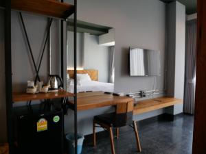 a bedroom with a bed and a desk and a bed and a table at OU HOTEL in Phitsanulok