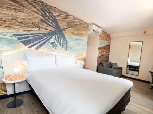1 dormitorio con 1 cama grande y reloj grande en la pared en ibis Styles Lima Benavides Miraflores, en Lima