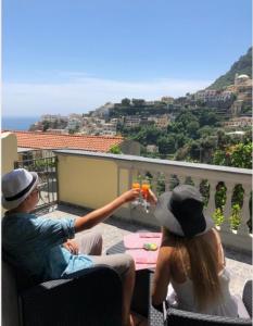 un uomo e una donna seduti a un tavolo su un balcone di Casa Tutti Frutti a Positano