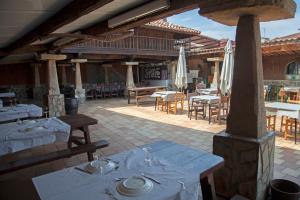 un restaurante con mesas blancas, sillas y sombrillas en Camping Las Gaviotas en Naveces