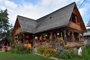 a house with flowers in the front yard at Pensiunea Maramu in Breb