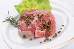 a piece of meat with peas on a white plate at Hotel Ristorante Toscana in Alassio