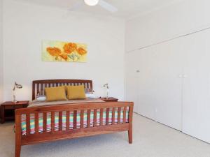 een slaapkamer met een houten bed en een schilderij aan de muur bij Castaways Beachfront house in Soldiers Point