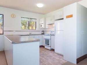 a kitchen with white cabinets and a white refrigerator at Commodore 9 so close to the waters egde in Shoal Bay +9 photos