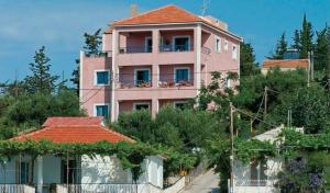 un bâtiment rose avec un balcon en haut. dans l'établissement Natassa Apartments, à Agia Effimia