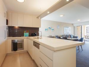 an open kitchen with white cabinets and a dining room at Cote D'Azure, 13 61 Donald Street - Lovely unit air con, Wi-Fi, secure parking, complex lift and pool in Nelson Bay