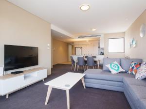 uma sala de estar com um sofá e uma televisão em Cote D'Azure, 13 61 Donald Street - Lovely unit air con, Wi-Fi, secure parking, complex lift and pool em Nelson Bay