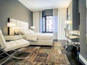 ウィーンにあるメルキュール ホテル ラファエル ウィーンのベッドルーム(白いベッド1台、デスク、椅子付)