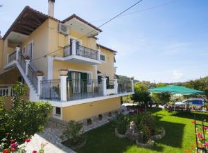 a yellow house with a balcony and a yard at Aliki Studios in Parga