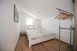 a white bedroom with a bed and a window at Apartments Center Opatija Ziric in Opatija