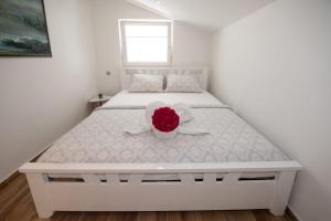 a white bed with a flower in a bowl on it at Apartments Center Opatija Ziric in Opatija