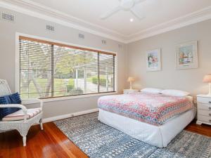 ein Schlafzimmer mit einem Bett, einem Fenster und einem Stuhl in der Unterkunft Dutchies Haven, 11 Christmas Bush Ave - Pet friendly, large enclosed yard, air con and Wi-Fi in Nelson Bay