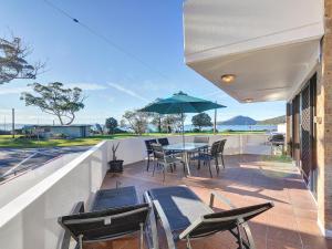 a patio with a table and chairs and an umbrella at Fleetwood 2 spectacular views in Shoal Bay
