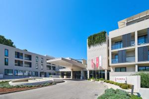 an apartment building with a driveway in front of it at Hotel Parentium Plava Laguna in Poreč