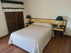 ein Schlafzimmer mit einem weißen Bett und zwei Nachttischen in der Unterkunft Hotel Urgeirica in Nelas