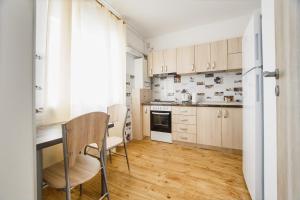 eine Küche mit Holzschränken sowie einem Tisch und Stühlen in der Unterkunft Sunny View 2 Bedroom Central Apartment in Oradea