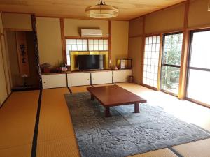 a living room with a table and a flat screen tv at 堺のお宿 旧星賀亭 in Kita-noda