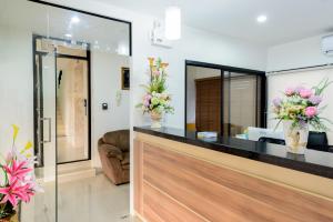 a lobby with a reception counter with flowers in vases at The Topaz Residence Phuket Town in Phuket Town