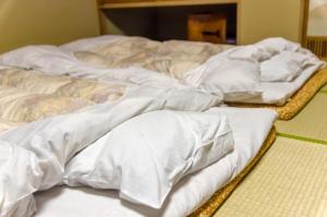 un grupo de mantas blancas sentadas en una cama en 堺のお宿 旧星賀亭, en Kita-noda