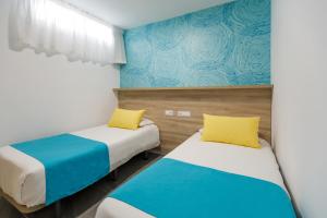 2 letti in una camera con blu e bianco di Alsol Guatiza a Playa del Ingles