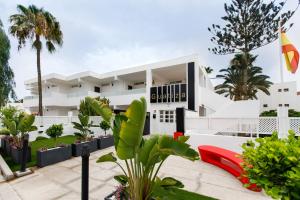 an exterior view of a white building with plants at Alsol Guatiza in Playa del Ingles