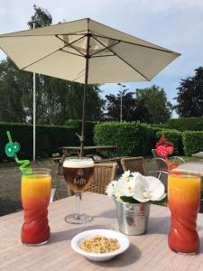 a table with an umbrella and a plate of food at The Originals City, Hôtel Le Gayant, Douai (Inter-Hotel) in Douai