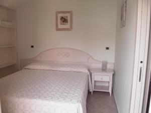 1 dormitorio con 1 cama y mesita de noche con colcha blanca en Residence Panama en Alassio