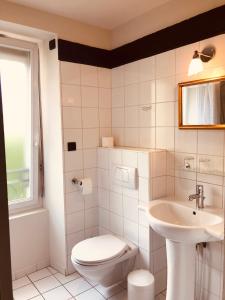 a white bathroom with a toilet and a sink at Hôtel Le Cobh in Ploërmel