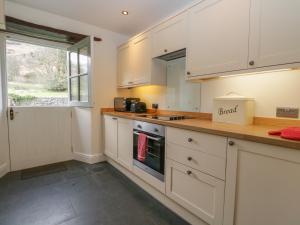 a kitchen with white cabinets and a counter top at Oak Tree Cottage in Coniston