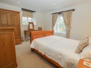 a bedroom with a bed and a dresser and windows at Oak Tree Cottage in Coniston