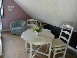 una mesa blanca con dos sillas y una mesa con flores. en Chambre d'Hotes La Queue au Loup, en Le Molay-Littry