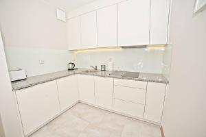 a white kitchen with white cabinets and a sink at Deluxe Modern Apartment Victoria Residence by Grand Apartments in Sopot