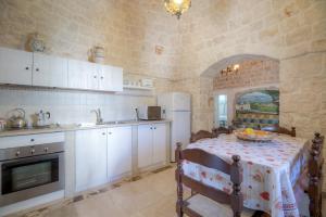 a kitchen with a table and a white refrigerator at Trulli La Piazzetta by Rentbeat in Cocolicchio