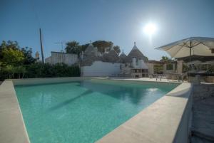 a swimming pool in a yard with an umbrella at Trulli La Piazzetta by Rentbeat in Cocolicchio