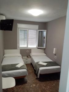 duas camas num quarto com duas janelas em AYAMONTE ROOMS 43 em Ayamonte