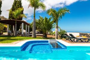 a swimming pool with palm trees and a resort at La Capellana in Tijarafe