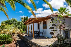 a small white house with a patio and palm trees at La Capellana in Tijarafe